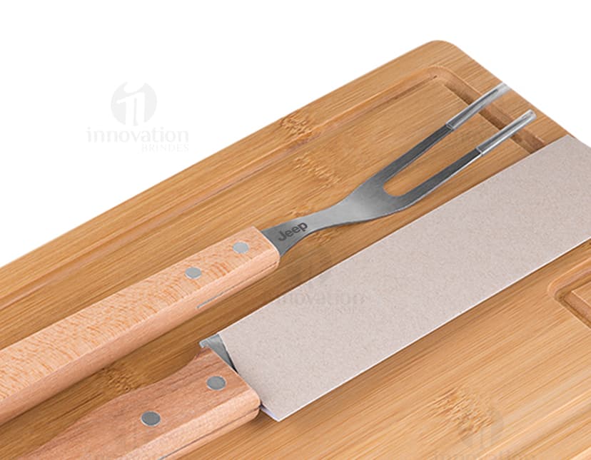 Kit churrasco composto por 3 peças (faca, garfo e espátula) e uma tábua de madeira.