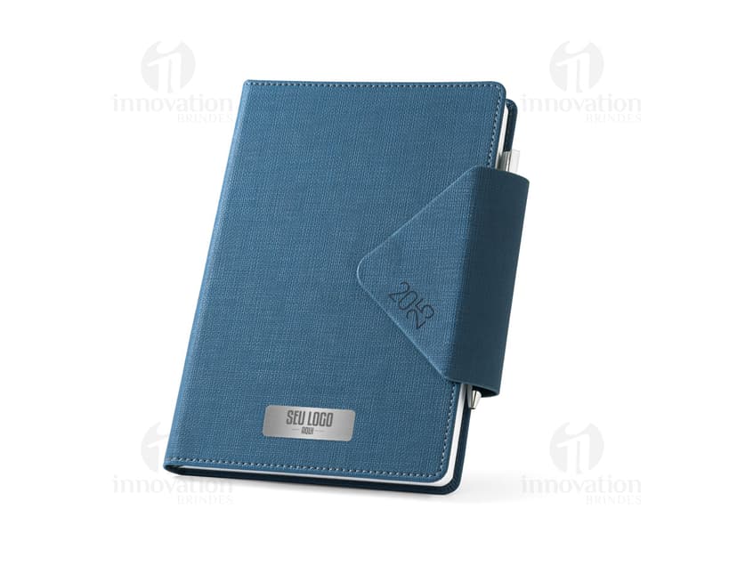 Agenda A5 preta com fecho magnético e suporte, ideal para armazenar informações e documentos de forma organizada. Fabricada em couro sintético, possui espaço para armazenar notas, dispositivos eletrônicos e cartões. Agenda compacta e elegante, perfeita para uso no escritório ou em viagens de negócios.