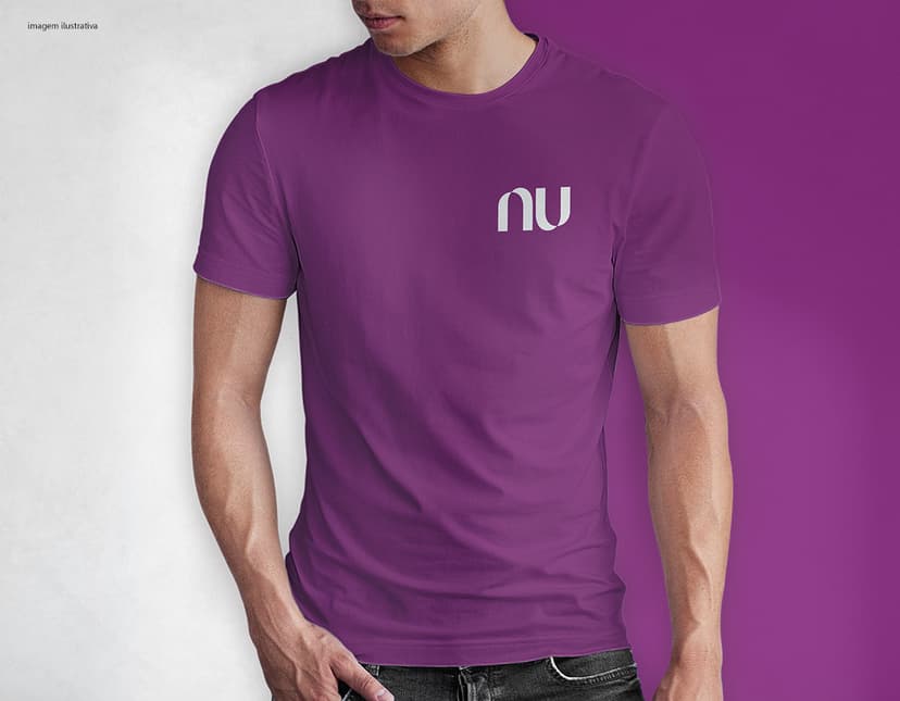 Homem jovem e atraente sorrindo, posando em um estúdio com uma camiseta preta de algodão tradicional de 165g/m². Ele está vestindo jeans, tem cabelo escuro e expressão feliz. O modelo está em pé, com um sorriso confiante, e possui uma aparência moderna e masculina.
