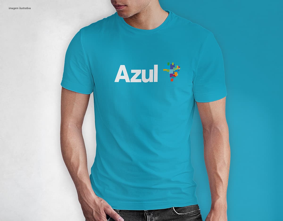 Homem jovem e atraente sorrindo, posando em um estúdio com uma camiseta preta de algodão tradicional de 165g/m². Ele está vestindo jeans, tem cabelo escuro e expressão feliz. O modelo está em pé, com um sorriso confiante, e possui uma aparência moderna e masculina.