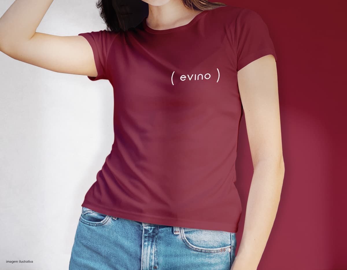 Camiseta feminina de corte cinturado em cor azul, usada por uma modelo sorridente e atraente. Ela está posando de forma casual e elegante, com cabelo escuro e jeans. A roupa é moderna e estilosa, perfeita para mulheres jovens e modernas.