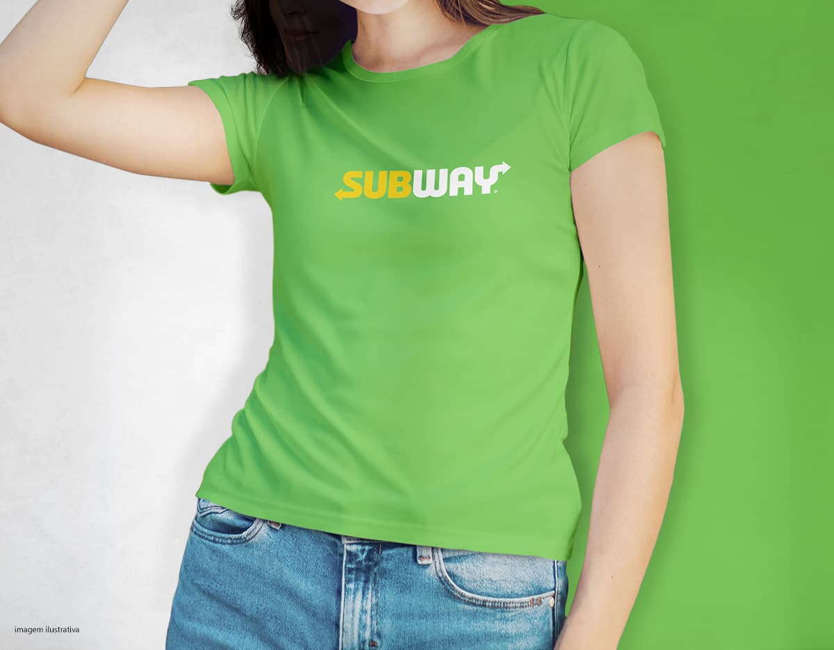 Camiseta feminina de corte cinturado em cor azul, usada por uma modelo sorridente e atraente. Ela está posando de forma casual e elegante, com cabelo escuro e jeans. A roupa é moderna e estilosa, perfeita para mulheres jovens e modernas.