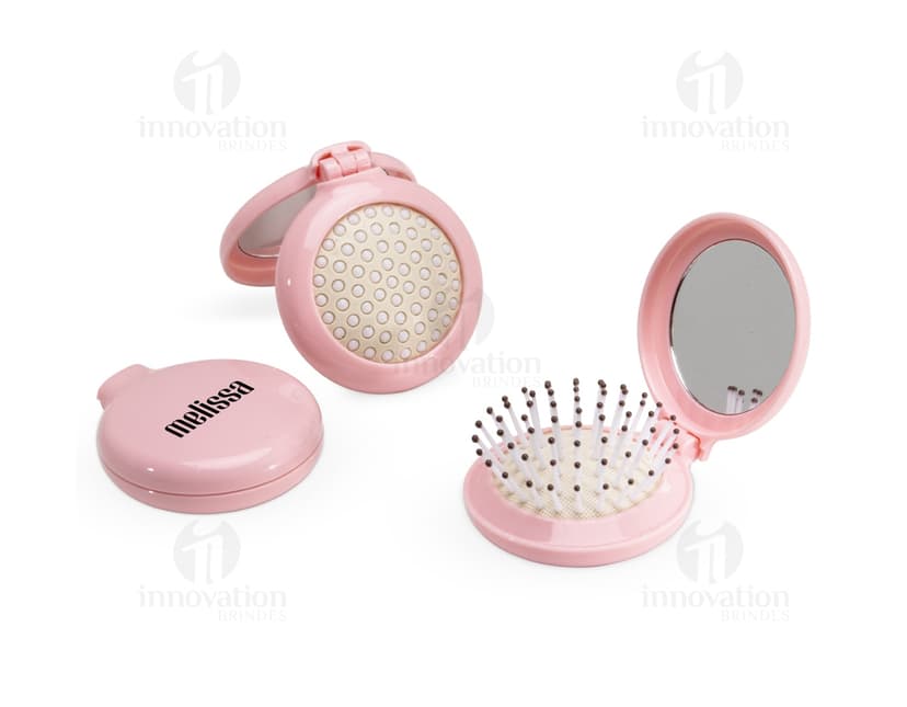 Escova com Espelho em metal prateado, design moderno e redondo, com espelho integrado. Ideal para uso como item de toiletry e maquiagem, com acabamento brilhante e símbolos em tons de preto e dourado.
