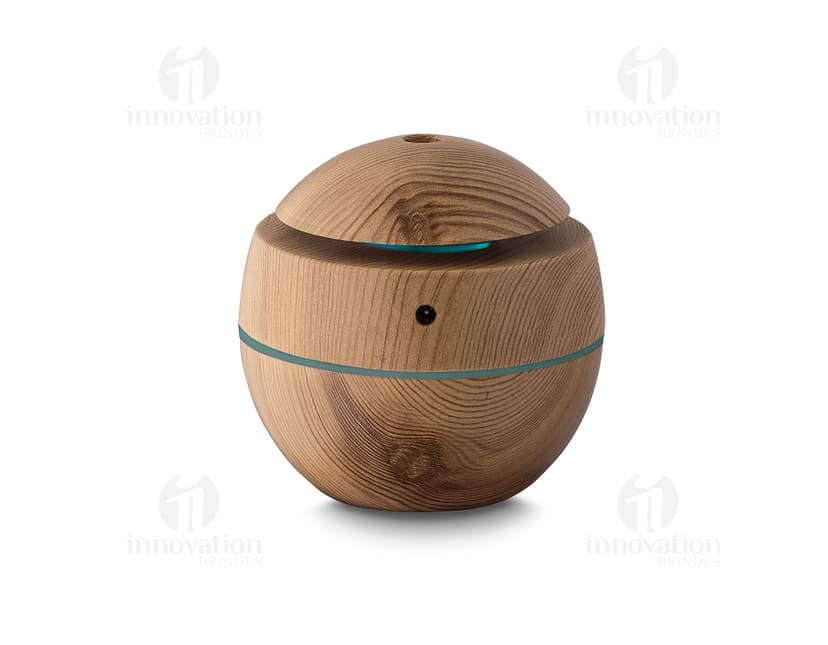 Umidificador de ar USB em ABS reciclável, que aparece em uma cesta de vime marrom ao lado de um banco, comida, dinheiro e outros objetos. A imagem é de vista próxima, com foco no produto e nos detalhes dos materiais utilizados.