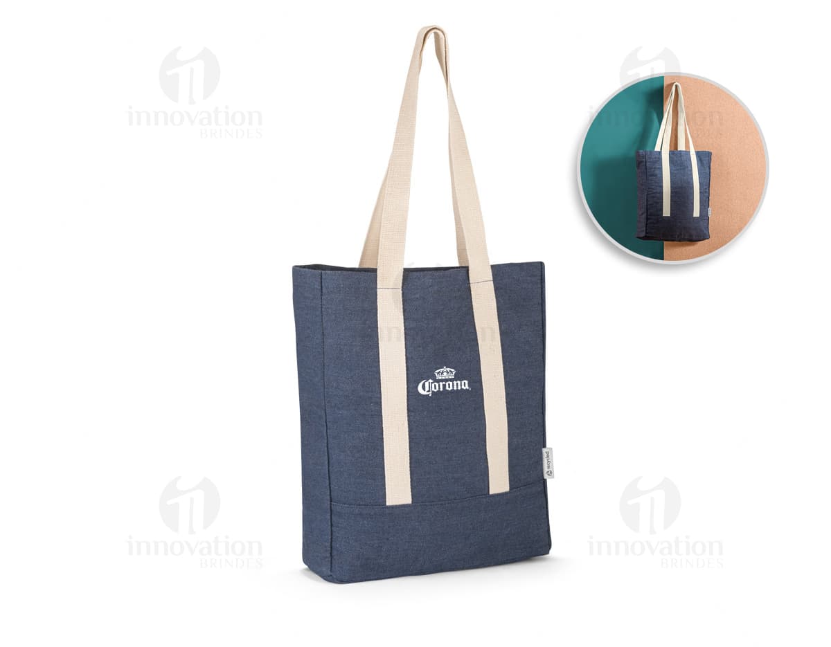 Sacola de denim reciclado com bolso, em tons de marrom e amarelo. Possui alça em couro, fecho com cadeado e etiqueta de preço. Ideal para compras e presente, demonstrando elegância e versatilidade.