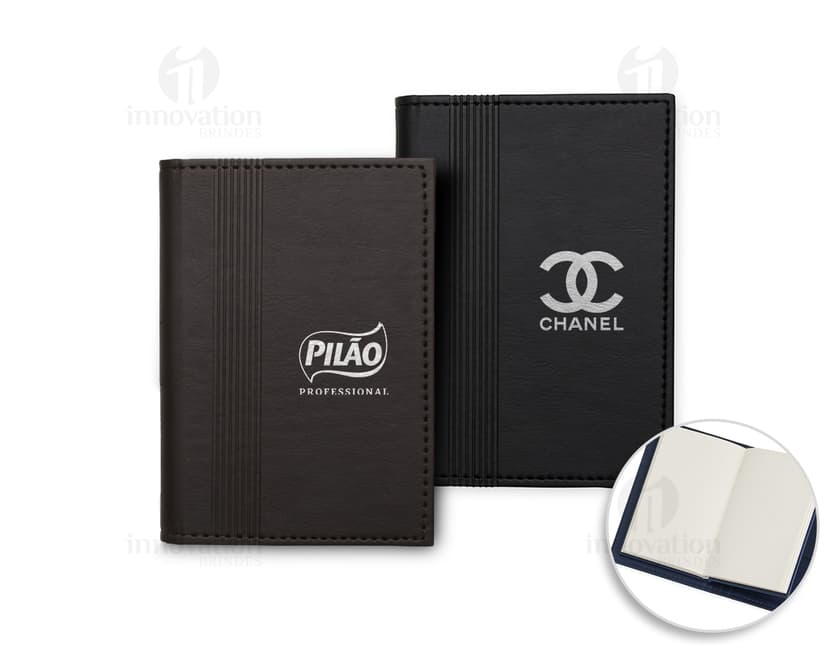 Bloco de anotações com porta caneta em um escritório vazio. O caderno está aberto em uma página em branco e ao lado há um videodisco. O design é moderno e conta com um espaço para guardar objetos, como canetas. O ambiente é limpo e organizado, com um ar de nostalgia.