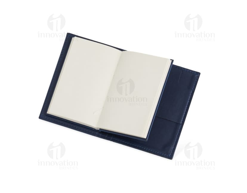Bloco de anotações com porta caneta em um escritório vazio. O caderno está aberto em uma página em branco e ao lado há um videodisco. O design é moderno e conta com um espaço para guardar objetos, como canetas. O ambiente é limpo e organizado, com um ar de nostalgia.