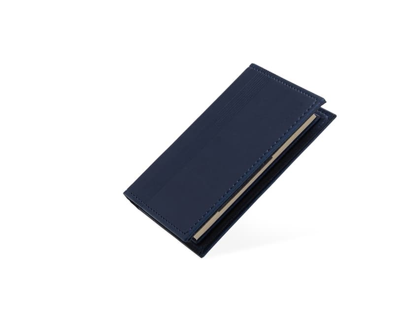Bloco de anotações com porta caneta em um escritório vazio. O caderno está aberto em uma página em branco e ao lado há um videodisco. O design é moderno e conta com um espaço para guardar objetos, como canetas. O ambiente é limpo e organizado, com um ar de nostalgia.