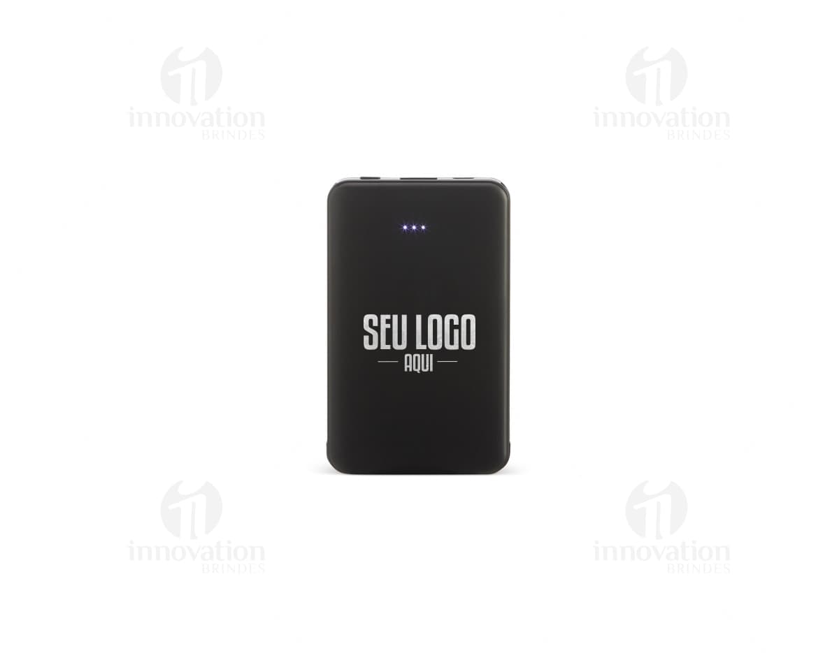 Power Bank Plástico 5.000mAh preto, dispositivo de tecnologia com adaptador e cabo de conexão. Equipamento eletrônico moderno para carregar dispositivos móveis. Visto contra um fundo de papel e teclado de computador.