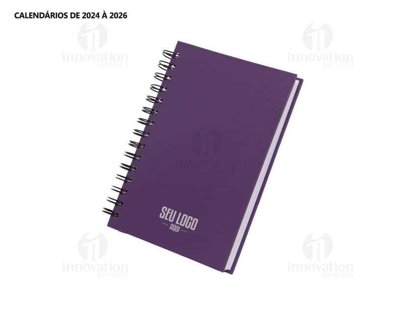 Agenda 2025 Cromato prata com design moderno e espaço para escrever notas, feita de metal resistente. Ao fundo, um campo de golfe e um notebook aberto com driver e roteador.