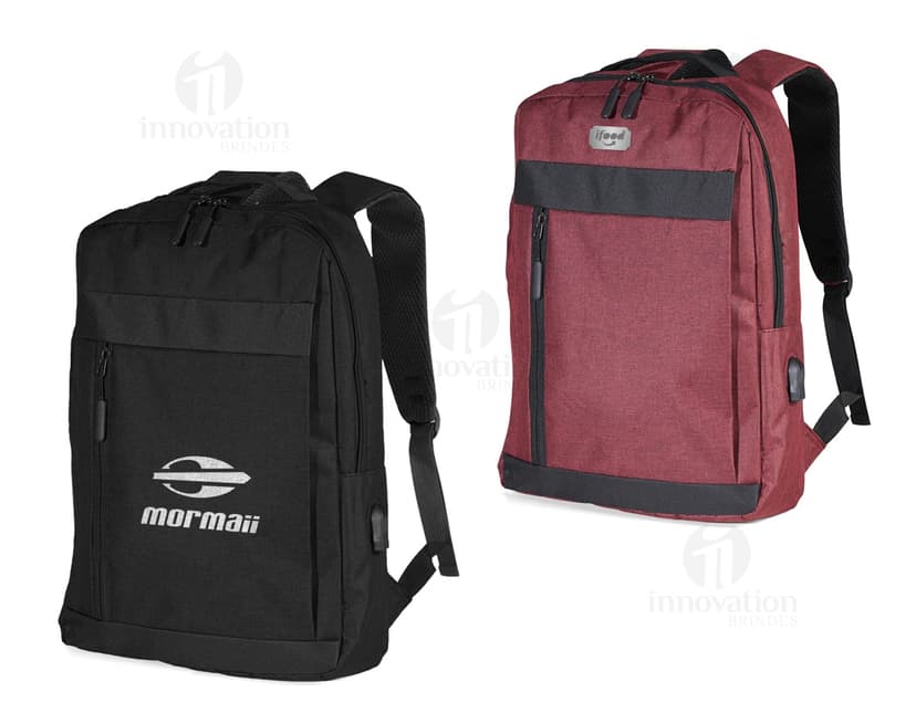 Homem de negócios usando um dispositivo eletrônico em um avião, com uma mochila de nylon preta nas costas. O bolso da mochila contém um cabo USB e há um jeans preto amarrado ao redor da alça.