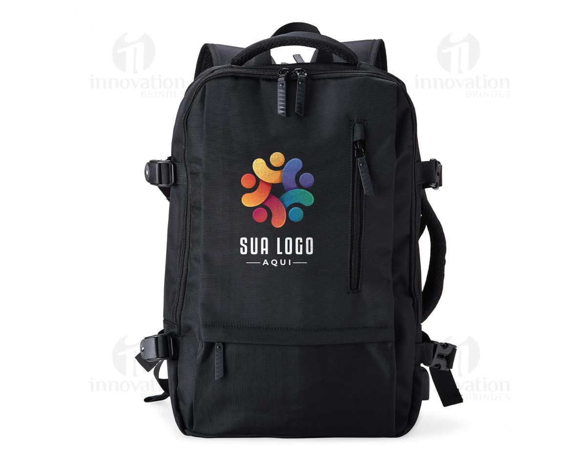 Homem de negócios usando um elegante terno preto, segurando uma mochila de nylon preta de 20 litros com USB. O acessório tem apoio nas costas, alça, e suporte para objetos.