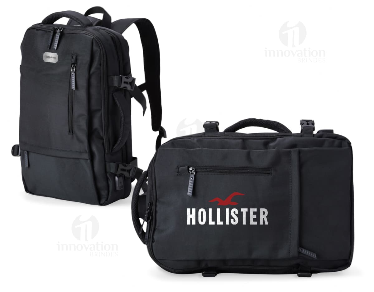 Homem de negócios usando um elegante terno preto, segurando uma mochila de nylon preta de 20 litros com USB. O acessório tem apoio nas costas, alça, e suporte para objetos.