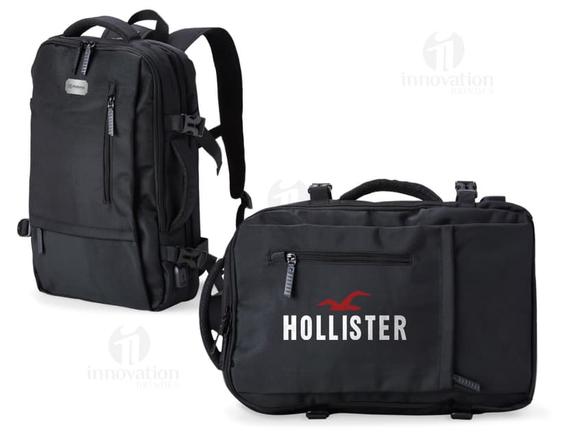 Homem de negócios usando um elegante terno preto, segurando uma mochila de nylon preta de 20 litros com USB. O acessório tem apoio nas costas, alça, e suporte para objetos.