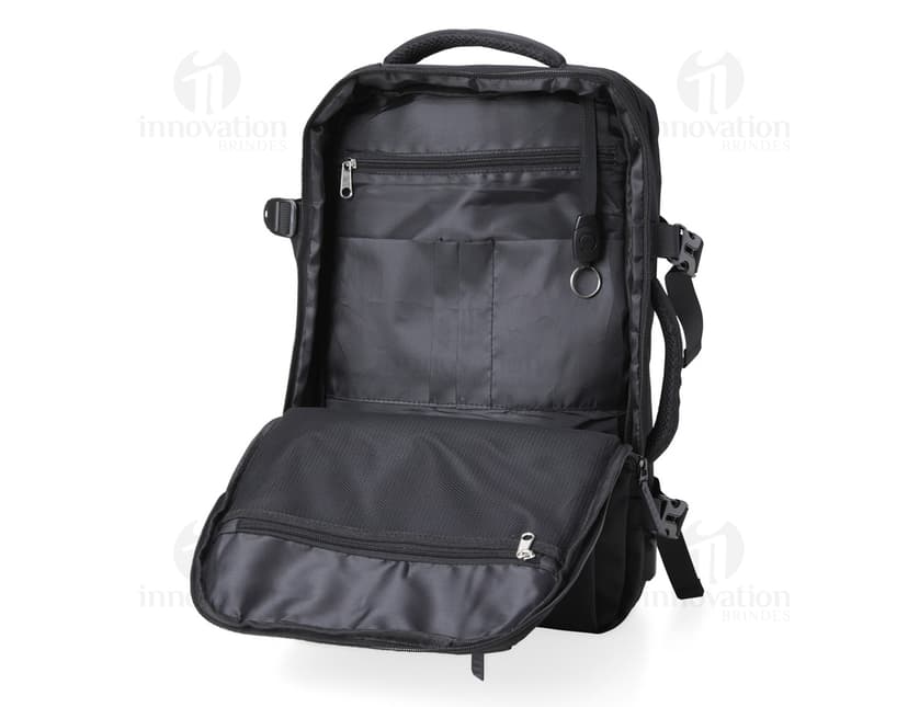 Homem de negócios usando um elegante terno preto, segurando uma mochila de nylon preta de 20 litros com USB. O acessório tem apoio nas costas, alça, e suporte para objetos.