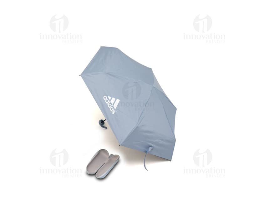Guarda chuva manual sendo segurado por uma pessoa sorridente em um escritório moderno com um computador e monitor ao fundo. O guarda chuva é preto e está aberto, sugerindo proteção contra a chuva. A pessoa está vestindo roupas profissionais e parece feliz. A imagem transmite a ideia de segurança e conforto em dias chuvosos.