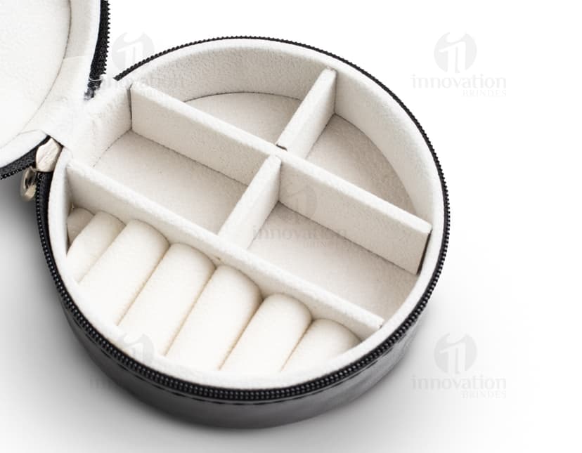 Um porta jóia de metal prateado, com tampa de vidro circular e lente de aumento embutida. O objeto possui um design tecnológico e futurista, com acabamento brilhante e textura de alumínio.É um recipiente de armazenamento para jóias e acessórios, ideal para manter suas peças protegidas e organizadas.