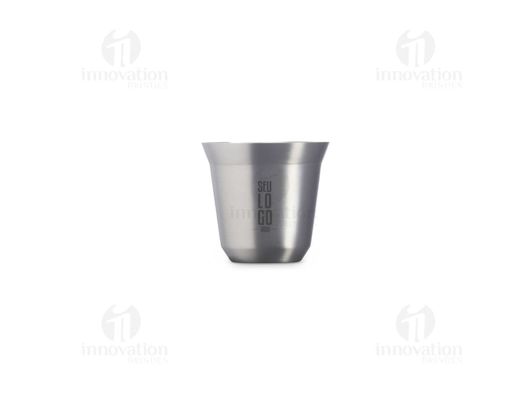 Copo de Inox de 100ml em uma mesa, ao lado de uma xícara de chá e diversos utensílios de cozinha. O copo está vazio, limpo e brilhante, com um design elegante.