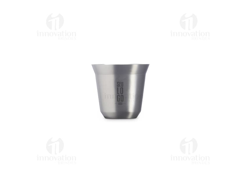 Copo de Inox de 100ml em uma mesa, ao lado de uma xícara de chá e diversos utensílios de cozinha. O copo está vazio, limpo e brilhante, com um design elegante.