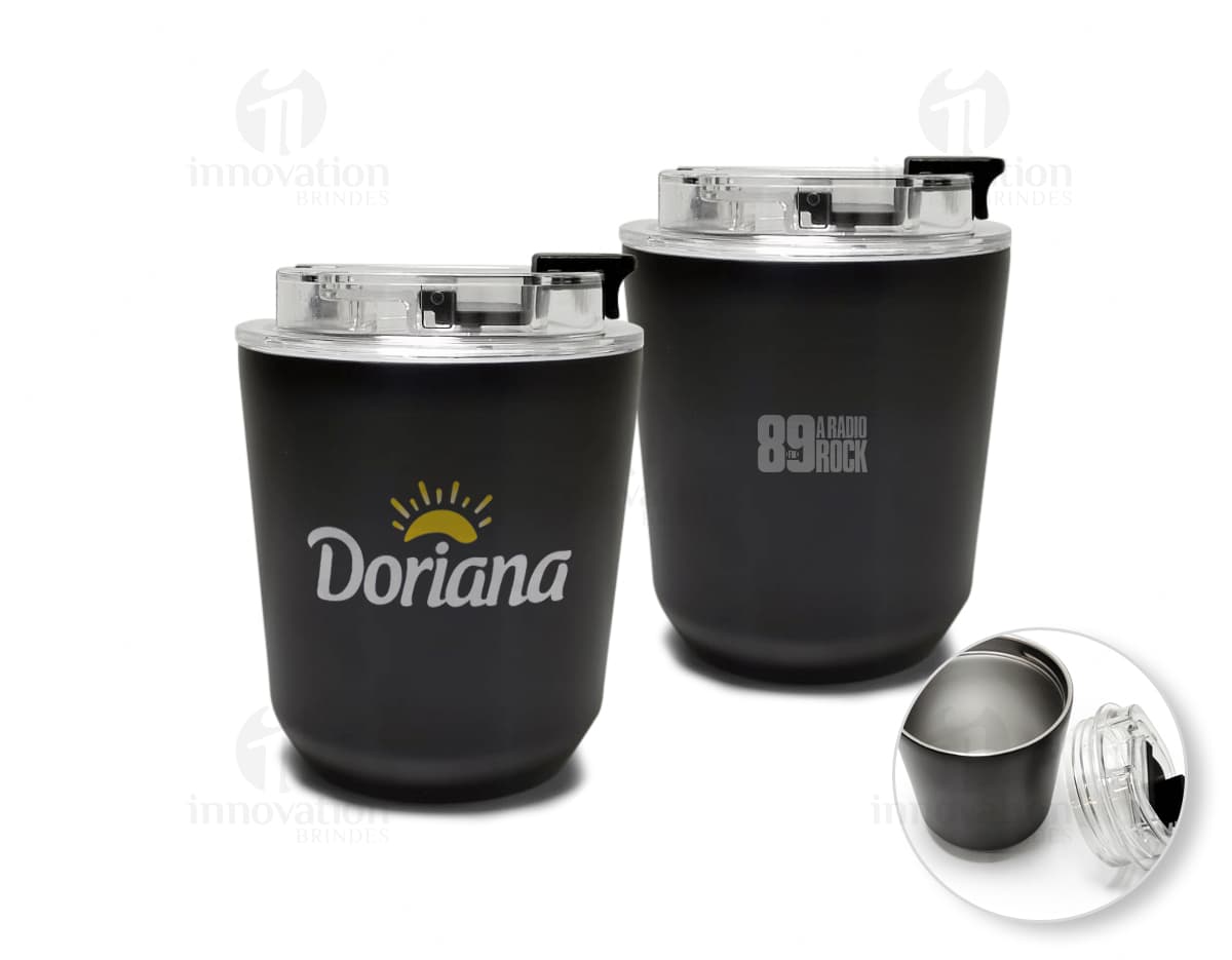 Copo térmico de 280ml em cerâmica preta e metal de cor prateada, com alça e tampa. O copo está vazio e posicionado sobre uma mesa de cozinha, ao lado de uma colher, uma jarra de café e alguns utensílios.