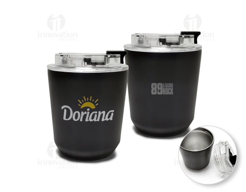 Copo térmico de 280ml em cerâmica preta e metal de cor prateada, com alça e tampa. O copo está vazio e posicionado sobre uma mesa de cozinha, ao lado de uma colher, uma jarra de café e alguns utensílios.
