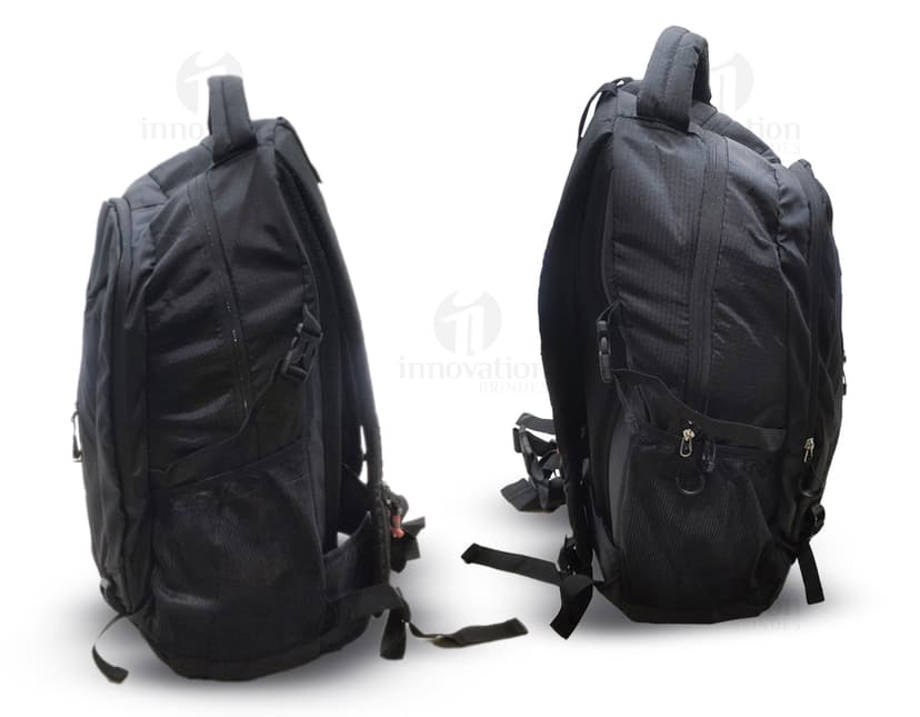 Homem usando mochila de nylon 43 litros em um estúdio. Ele está sorrindo e parece confiante, vestindo um terno preto e uma jaqueta de couro.