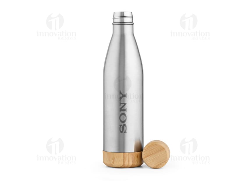 Garrafa de aço inox com rótulo vazio, contendo líquido transparente. Próximo a um copo de bebida alcoólica, em um ambiente elegante e refinado.