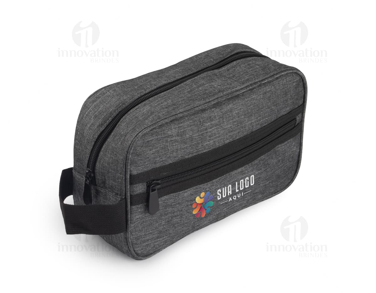 Necessaire de couro preta contendo dispositivos eletrônicos, adaptadores, instrumentos, dinheiro, estojo de câmera, papel, carteira pessoal e outros acessórios. O objeto está fechado e possui fecho de correr.