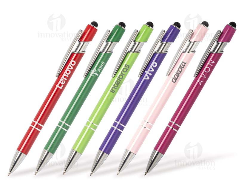 Caneta metal touch em diversas cores sobre uma mesa de escritório, ao lado de um bloco de notas, lápis e papel.