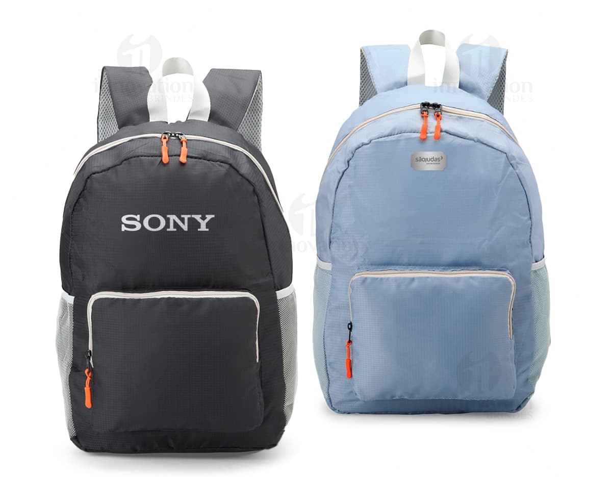 Mochila de Nylon Dobrável 23 Litros preta sendo segurada por um homem sorrindo, em um estúdio. O produto é um equipamento de viagem e possui zíper, alça, e é adequado para hiking, escola, negócios e lazer.