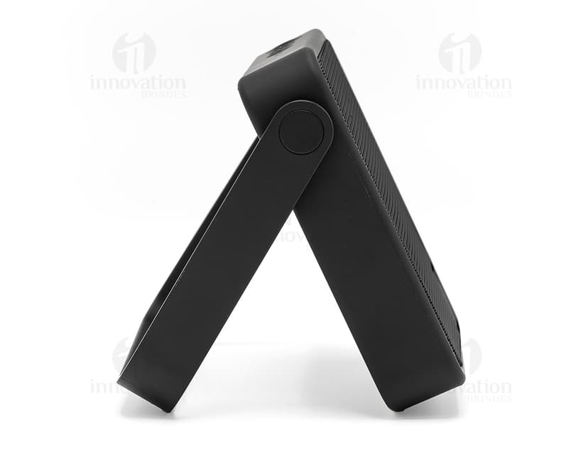 Caixa de som preta com botões de controle de volume e conexão Bluetooth no lado direito e textura de tecido na parte frontal.