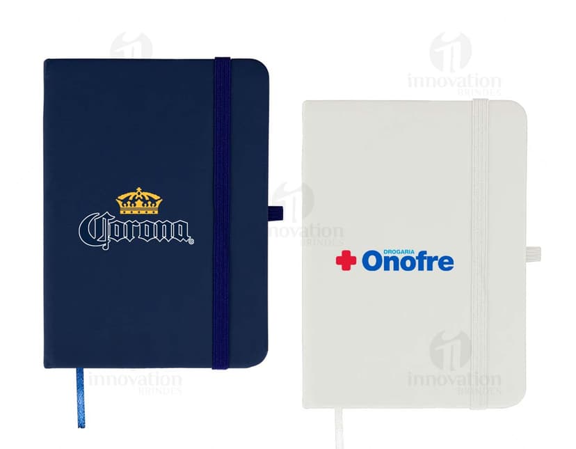 Caderneta emborrachada preta com design vintage, vazia e com textura grunge. Aparecem um notebook, um metrônomo, uma guitarra, uma página em branco e um pendulo.