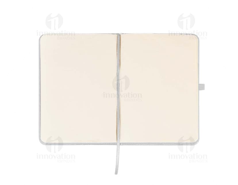 Caderneta emborrachada preta com design vintage, vazia e com textura grunge. Aparecem um notebook, um metrônomo, uma guitarra, uma página em branco e um pendulo.