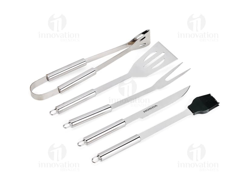 Kit Churrasco 5 Peças - Conjunto contendo faca, garfo, pinça, espátula e escova para churrasco em fundo de madeira.